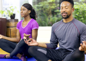 Attractive African american couple meditating after their workout