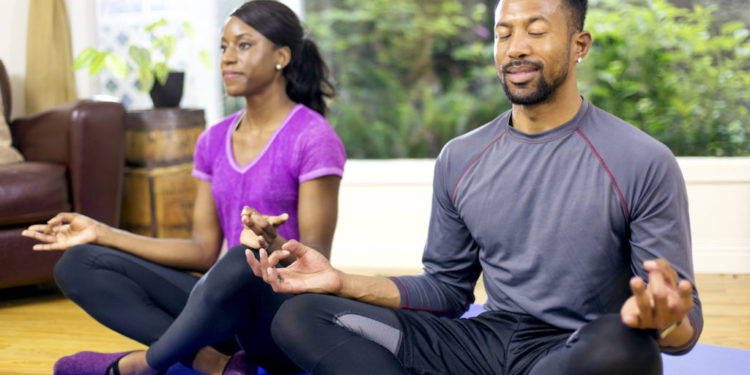Attractive African american couple meditating after their workout