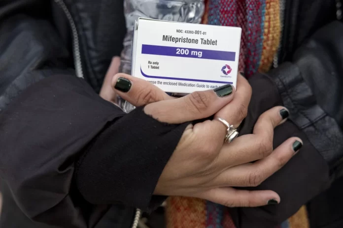 An abortion- rights activist holds a box of mifepristone pills as demonstrators from both anti-abortion and abortion-rights groups rally outside the Supreme Court in Washington, Tuesday, March 26, 2024. (AP Photo/Amanda Andrade-Rhoades,File)