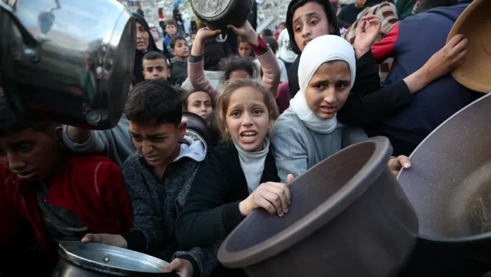 Palestinians wait in line to receive hot food, at Jabalya refugee camp on March 4, 2025. Mahmoud Ssa/Anadolu/Getty Images