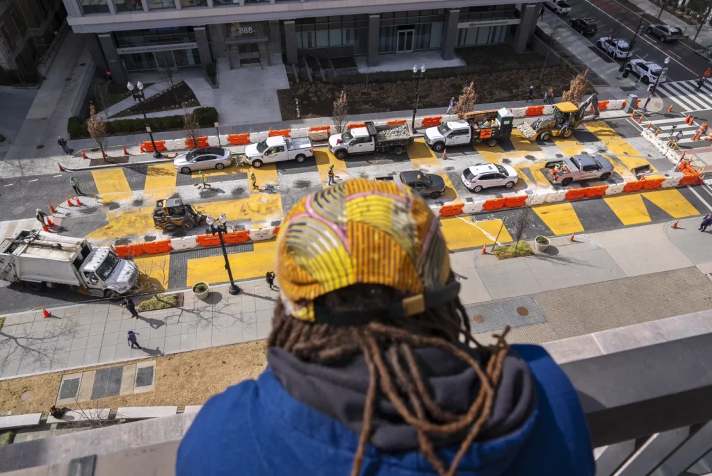From the top of a building, Kanon Kennedy, of Washington, looks down at the Black Lives Matter mural as demolition begins, Monday, March 10, 2025, in Washington. (AP News)