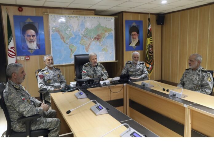 In this photo released on Monday, June 23, 2025, by Iranian army press service, Iran's army commander-in-chief Gen. Amir Hatami, center, accompanied by high ranked army commanders, speaks in a video call with top commanders of the army, in Zolfaghar central headquarters, Iran, as portraits of the late revolutionary founder Ayatollah Khomeini, left, and Supreme Leader Ayatollah Ali Khamenei hang on the wall. (Iranian Army Press Service via AP)