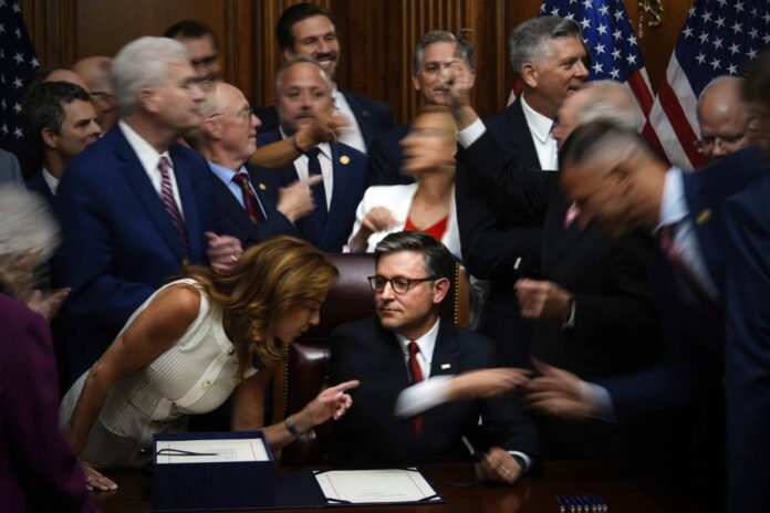 Republican members of Congress reach to shake hands with Speaker of the House Mike Johnson, R-La., center bottom, after Johnson signed the President Donald Trump’s signature bill of tax breaks and spending cuts, Thursday, July 3, 2025, at the Capitol in Washington. (AP Photo/Julia Demaree Nikhinson)