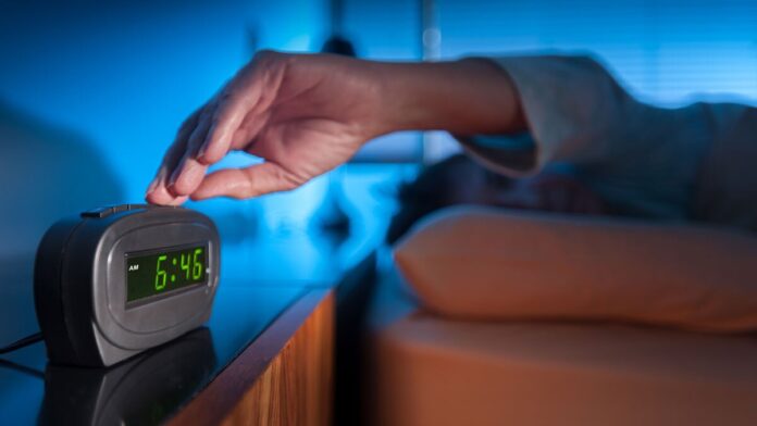 A man sleeping peacefully in bed as morning light filters through the window, symbolizing the effects of daylight saving time on rest and sleep patterns.