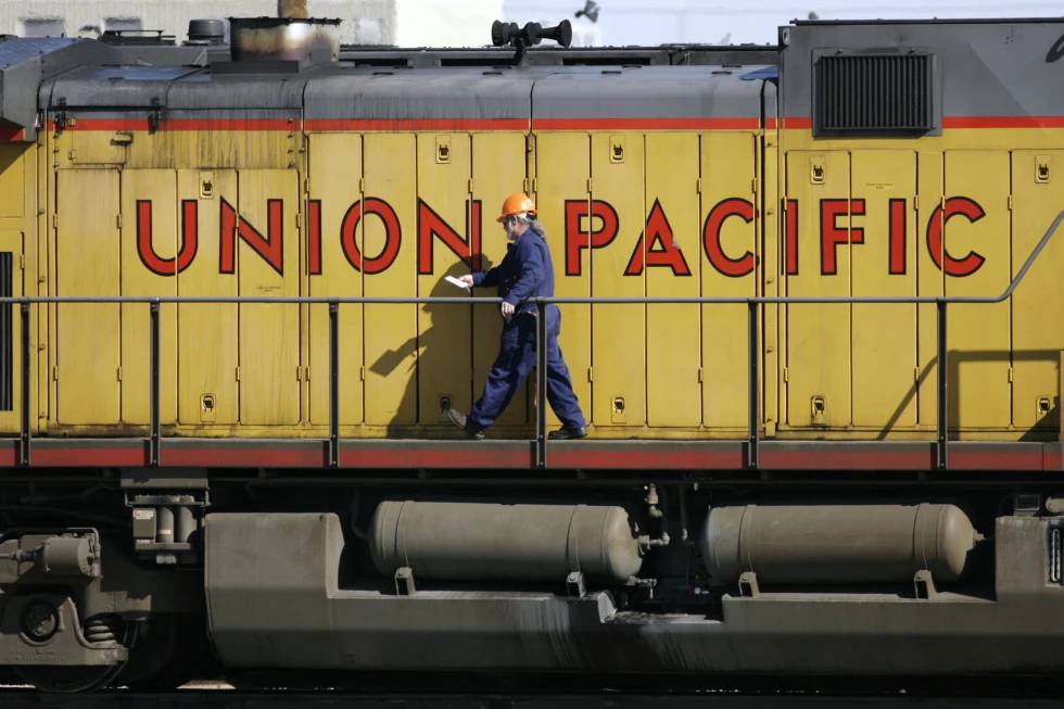 A maintenance worker walks past the company logo on the side of a locomotive in the Union Pacific Railroad fueling yard in north Denver, Oct. 18, 2006. (AP Photo/David Zalubowski, File)