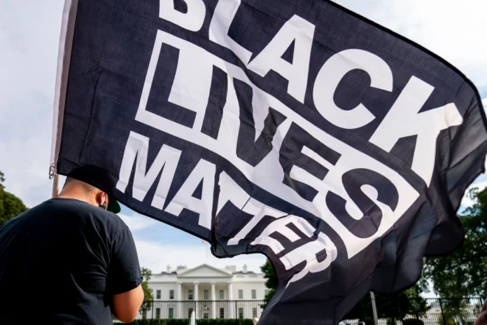 A man carries a Black Lives Matter flag in Lafayette Square outside the White House on the fourth night of the Republican National Convention, Aug. 27, 2020, in Washington. (AP Photo/Andrew Harnik, File)