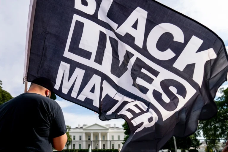 A man carries a Black Lives Matter flag in Lafayette Square outside the White House on the fourth night of the Republican National Convention, Aug. 27, 2020, in Washington. (AP Photo/Andrew Harnik, File)