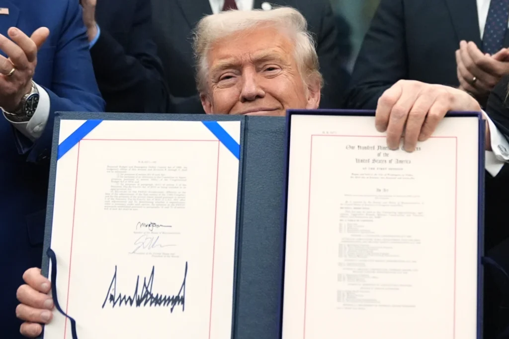 President Donald Trump displays the signed the funding bill to reopen the government, in the Oval Office of the White House, Wednesday, Nov. 12, 2025, in Washington. (AP Photo/Jacquelyn Martin)