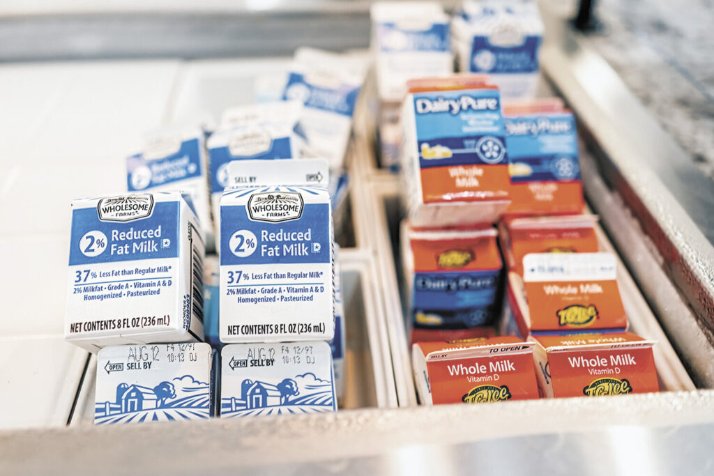 Whole milk and 2% milk cartons lined up in a school cafeteria cooler following the Whole Milk for Healthy Kids Act policy change.