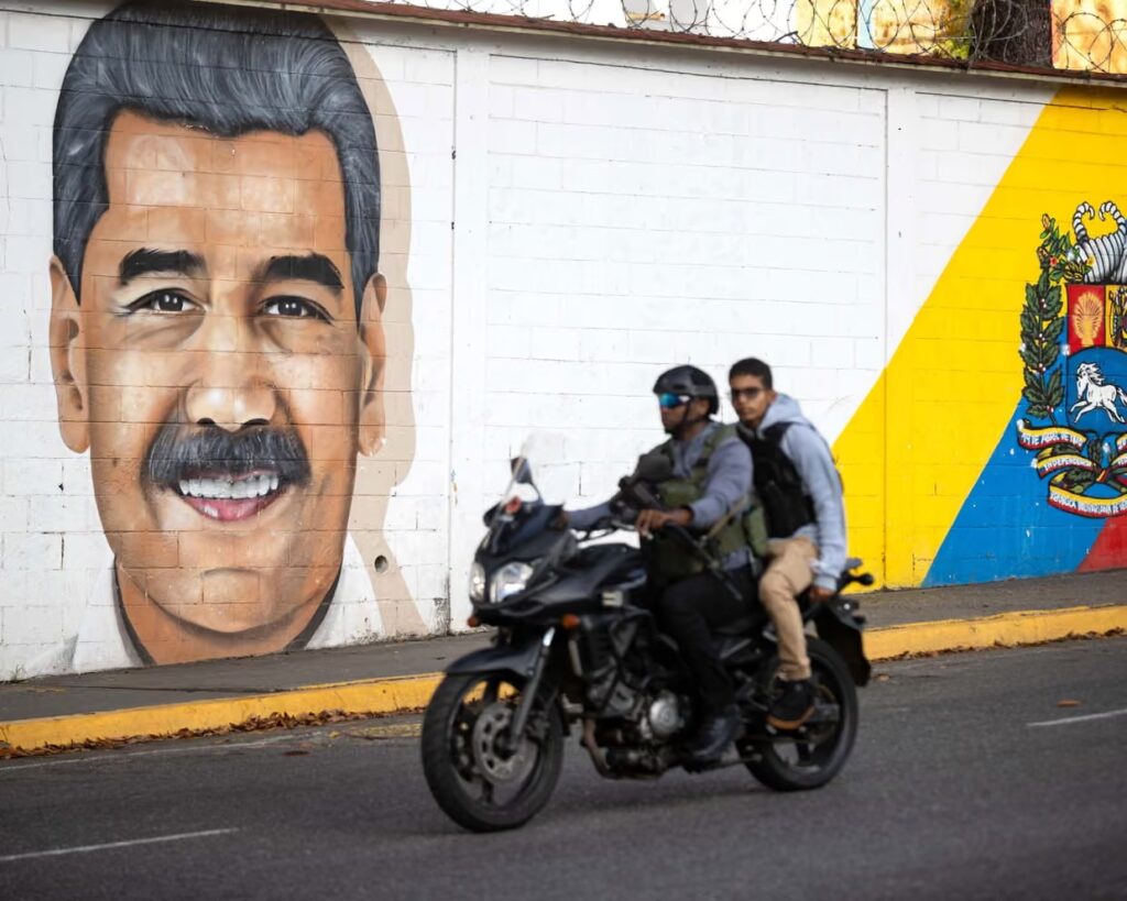 People ride a motorbike past a mural of Venezuelan President Nicolás Maduro in Caracas, Venezuela, on Sunday. Photograph: Ronald Pena R/EPA