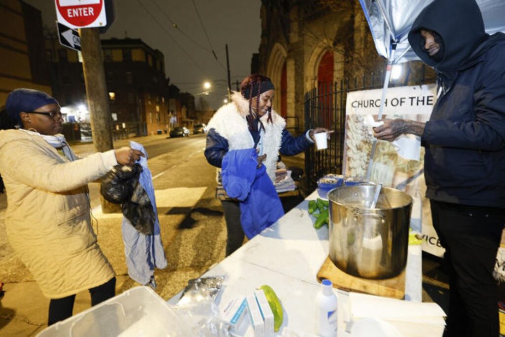 Philadelphia Black Panther Party for Self-Defense member Skiippy, right, hands soup to Yolanda Gray, middle, and Roxanne Hart outside the Church of the Advocate in North Philadelphia on Jan. 9, 2026. Yong Kim/The Philadelphia Inquirer/TNS