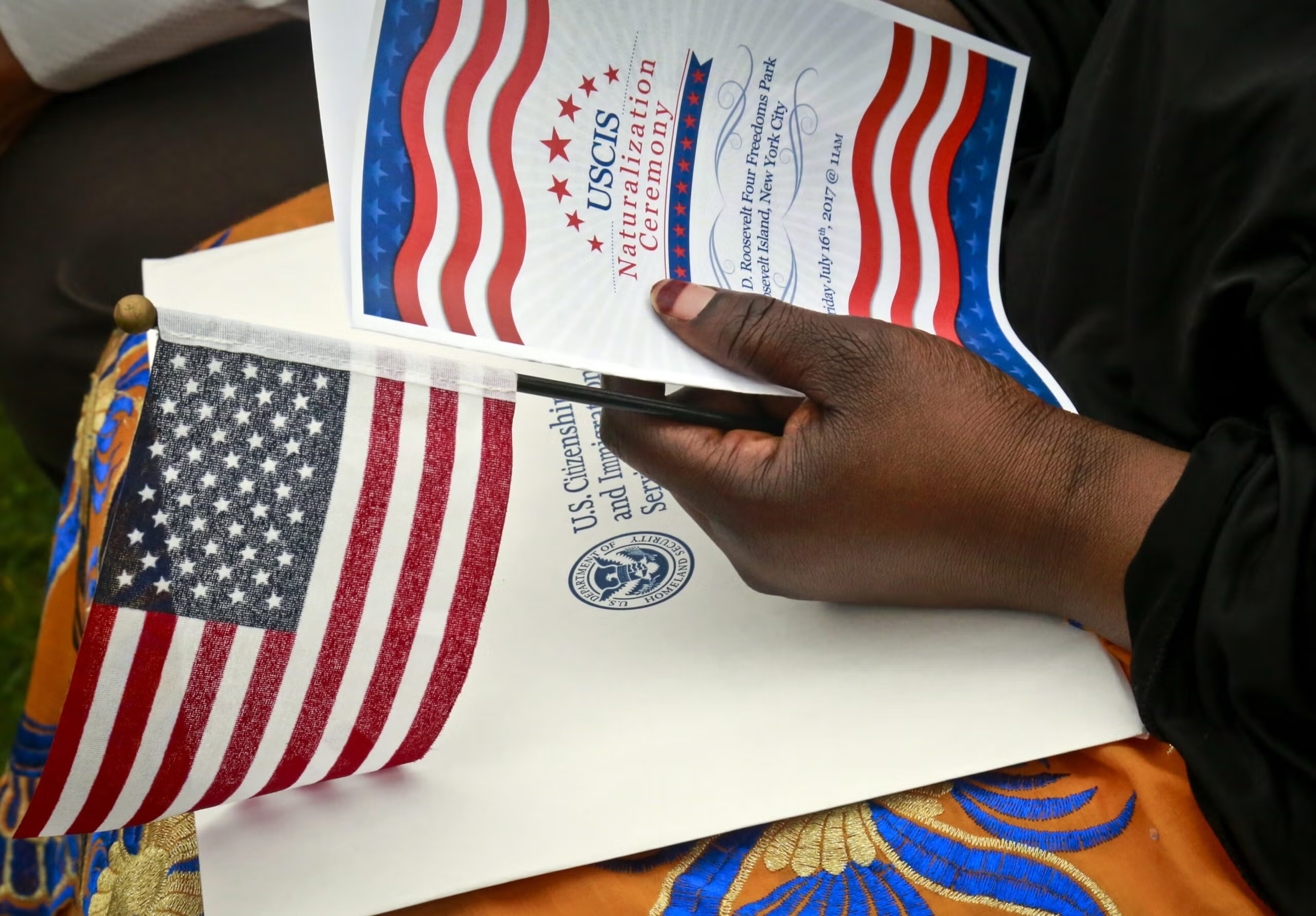 Fatoumata Jangana, from Gambia, holds a program and flag during U.S. Citizen and Immigration Services ceremony for 50 new citizens from 24, Friday June 16, 2017, in New York. Jangana became a citizen after 21 years in the U.S. Bebeto Matthews/AP Photo