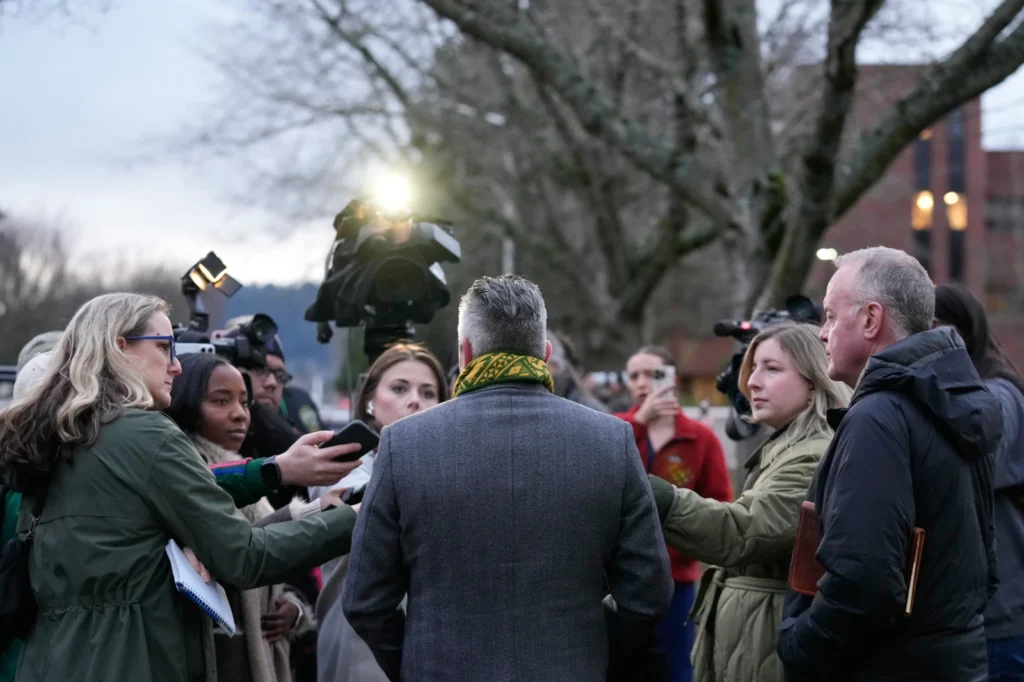 Multnomah County District Attorney Nathan Vasquez, center, speaks to the media following reports that federal immigration officers shot and wounded people in Portland, Ore., Thursday, Jan. 8, 2026. (AP Photo/Jenny Kane)