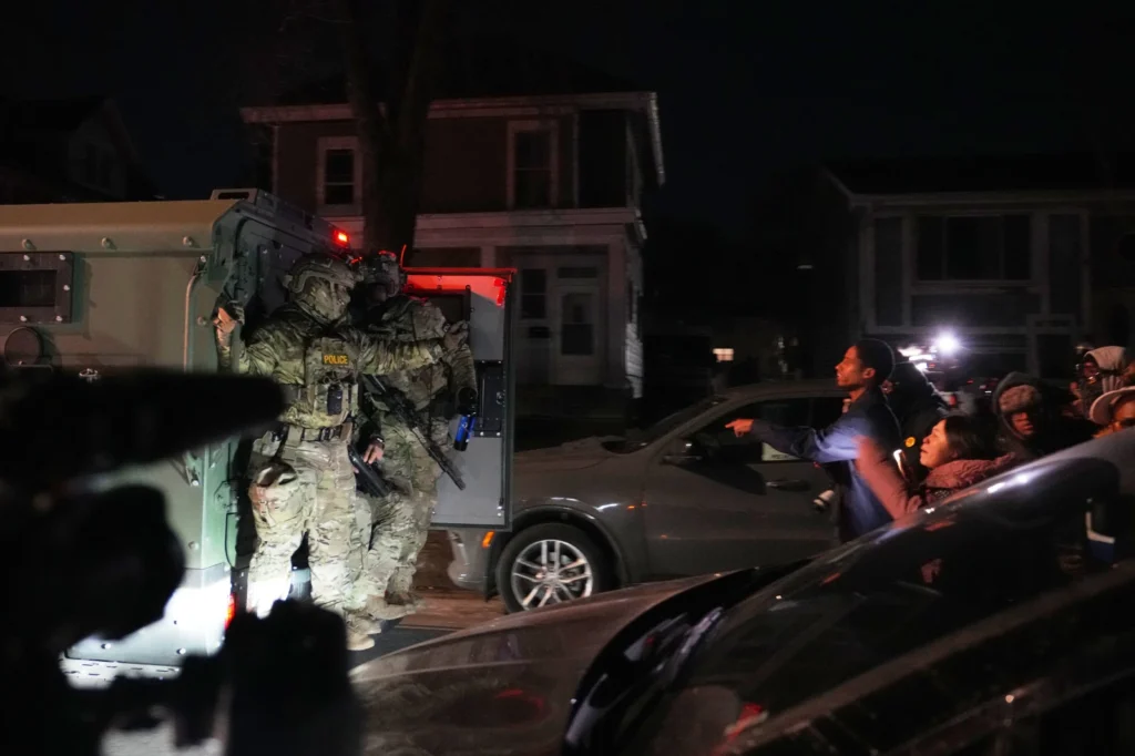Protesters shout at law enforcement officers after a shooting on Wednesday, Jan. 14, 2026, in Minneapolis. (AP Photo/Abbie Parr)