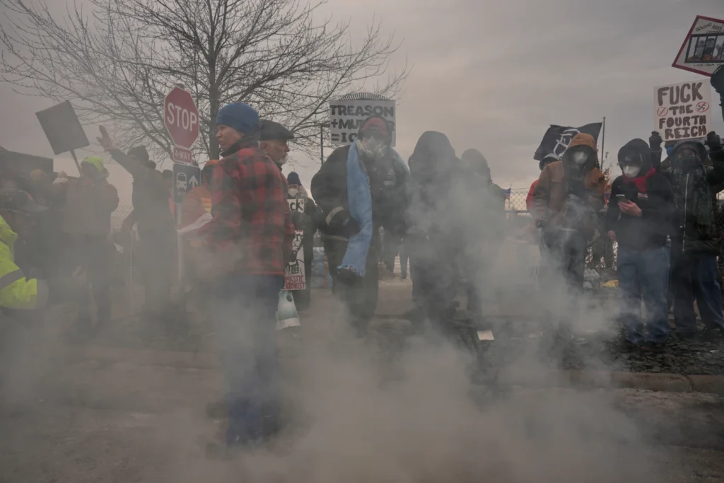 People cover tear gas deployed by federal immigration officers outside Bishop Henry Whipple Federal Building, Thursday, Jan. 15, 2026, in Minneapolis. (AP Photo/Adam Gray)