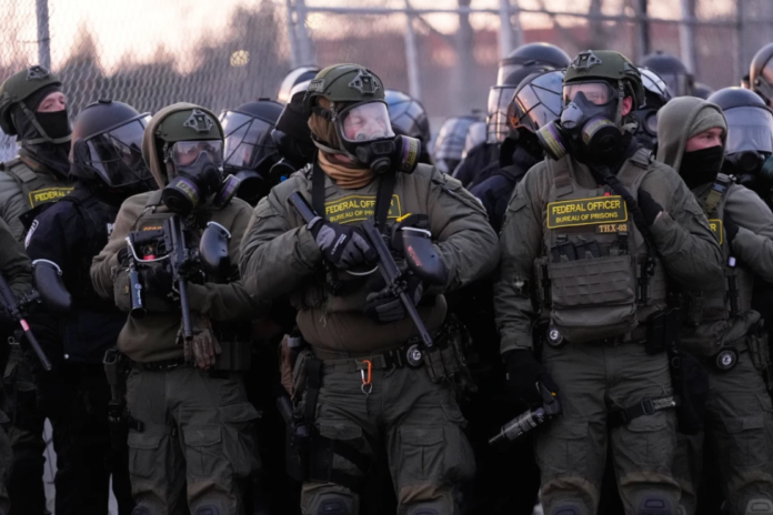 Federal officers stand outside the Bishop Henry Whipple Federal Building during a protest on Saturday, Jan. 17, 2026, in Minneapolis. (AP Photo/Yuki Iwamura)