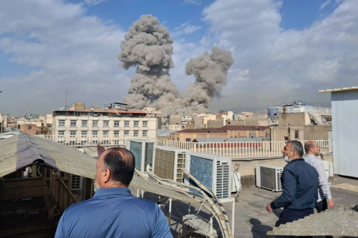 People watch as smoke rises on the skyline after an explosion in Tehran, Iran, Saturday, Feb. 28, 2026. (AP Photo)