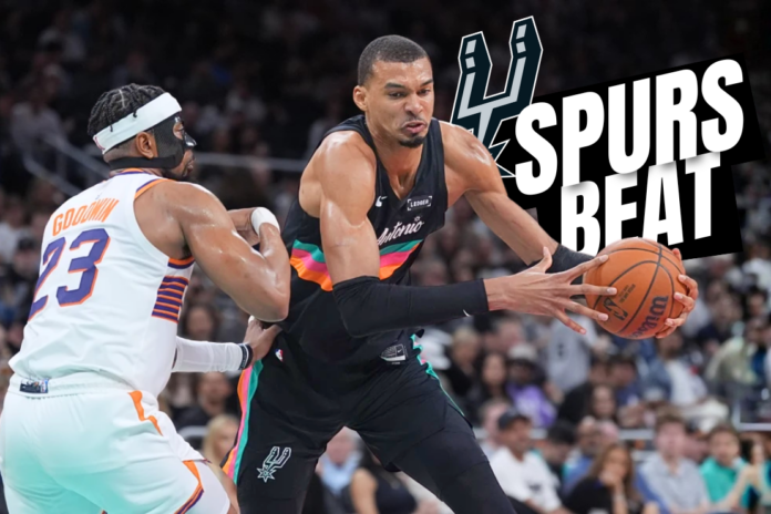 San Antonio Spurs forward Victor Wembanyama (1) drives against Phoenix Suns guard Jordan Goodwin (23) during the second half of an NBA basketball game in Austin, Texas, Thursday, Feb. 19, 2026. (AP Photo/Eric Gay)