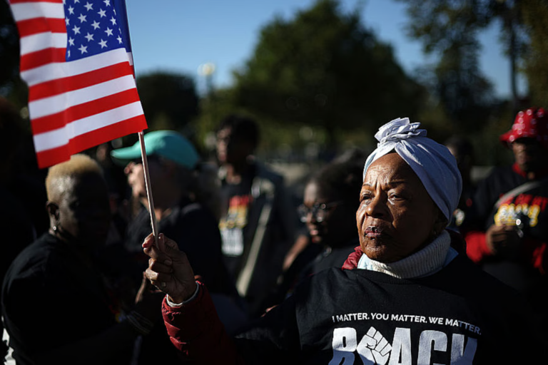 An activist holds a U.S. flag during a rally in front of the U.S. Supreme Court on October 15, 2025 in Washington, DC. The Supreme Court is scheduled to hear oral arguments in Louisiana v. Callais, a major case concerning a congressional map that created a second majority-Black district in Louisiana. (Photo by Alex Wong/Getty Images)