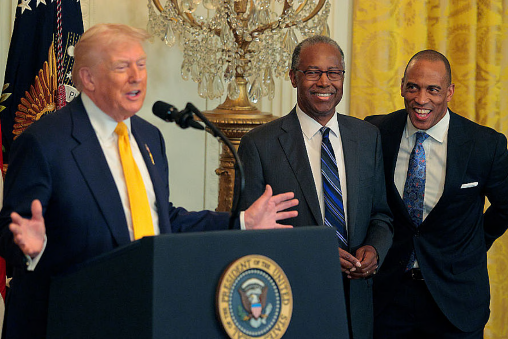 U.S. President Donald Trump speaks as Former Housing and Urban Development Secretary Dr. Ben Carson (C) and U.S. Secretary of Housing and Urban Development Scott Turner look on during a Black History Month reception in the East Room of the White House on February 18, 2026 in Washington DC. (Photo by Chip Somodevilla/Getty Images)