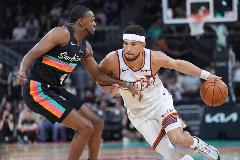 Phoenix Suns guard Devin Booker (1) drives against San Antonio Spurs guard De'aaron Fox (4) during the first half of an NBA basketball game in Austin, Texas, Thursday, Feb. 19, 2026. (AP
Photo/Eric Gay)
