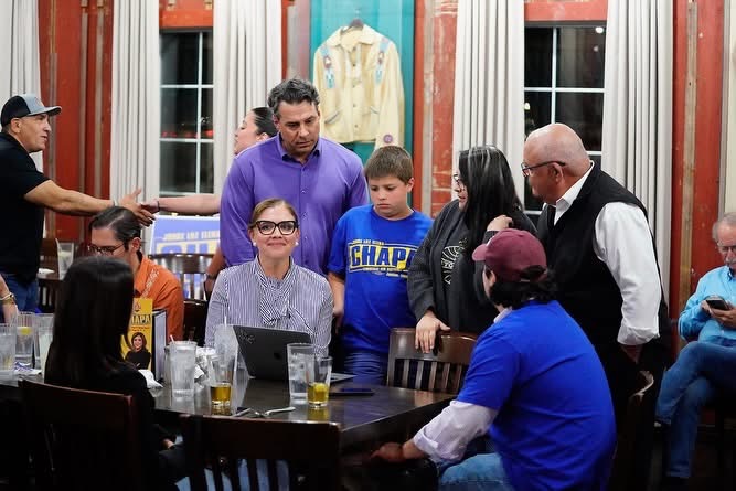 Luz Elena Chapa sits at a table speaking with supporters and family during her election night watch party on March 6