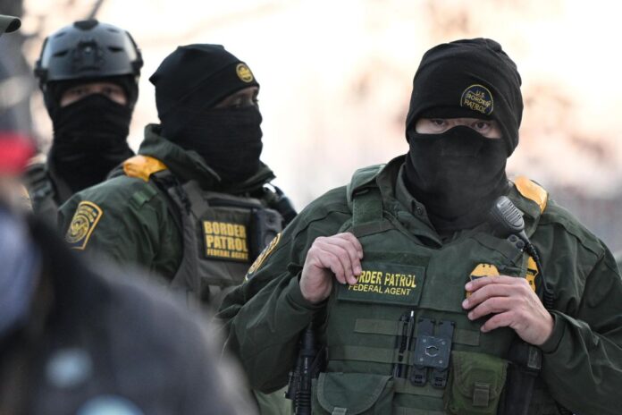 Federal agents look on as protesters gather outside the Bishop Henry Whipple Federal Building, Thursday, Jan. 8, 2026, in Minneapolis, Minn. (AP Photo/Tom Baker, File)