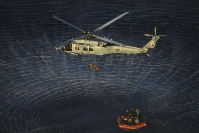 Artemis II astronauts are lifted by helicopter from a raft to a recovery ship after splashdown in the Pacific Ocean near San Diego.