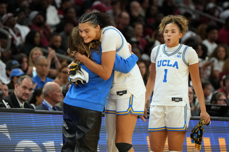 UCLA head coach Cori Close, left, hugs UCLA center Lauren Betts (51) during the second half of the women's National Championship Final Four NCAA college basketball tournament game against South Carolina, Sunday, April 5, 2026, in Phoenix. (AP Photo/Rick Scuteri)