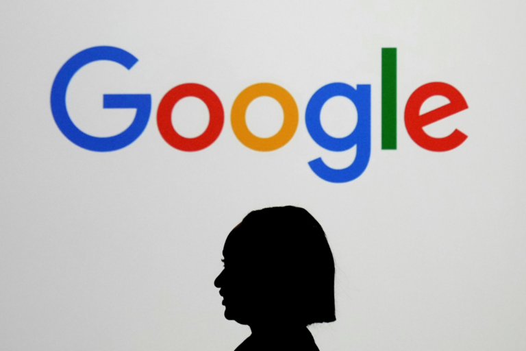 A woman walks by a giant screen displaying the Google logo at an event at the Paris Google Lab on the sidelines of the Al Action Summit in Paris, Feb. 9, 2025. (AP Photo/Thibault Camus, File)