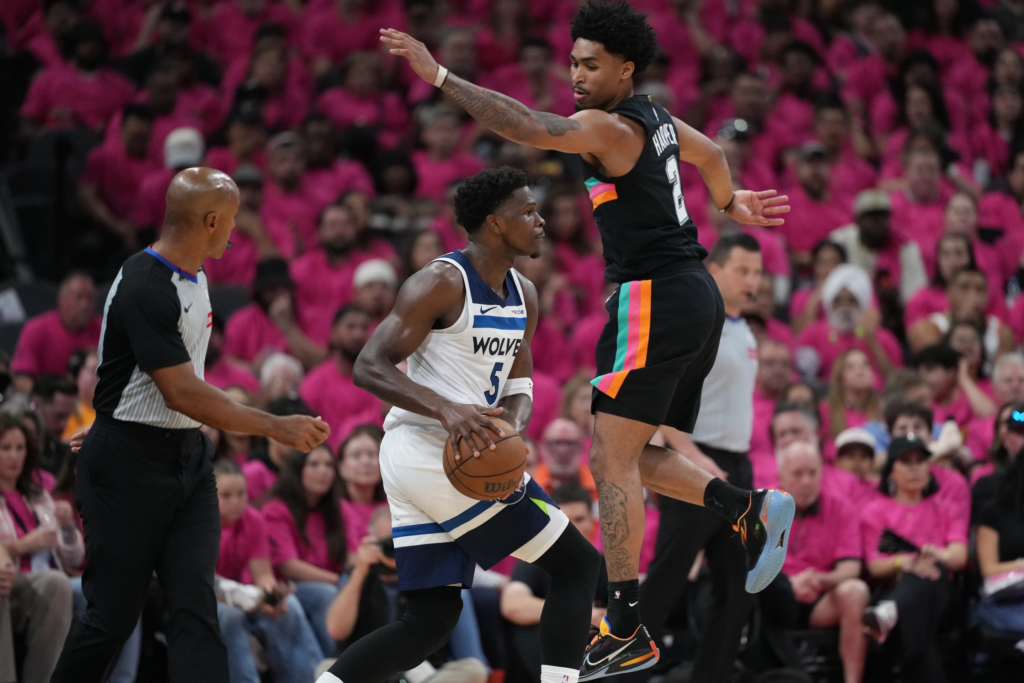 Minnesota Timberwolves guard Anthony Edwards (5) handles the ball as San Antonio Spurs guard Dylan Harper (2) defends during the first half in Game 1 of a second-round NBA playoffs basketball series in San Antonio, Monday, May 4, 2026. (AP Photo/Eric Gay)