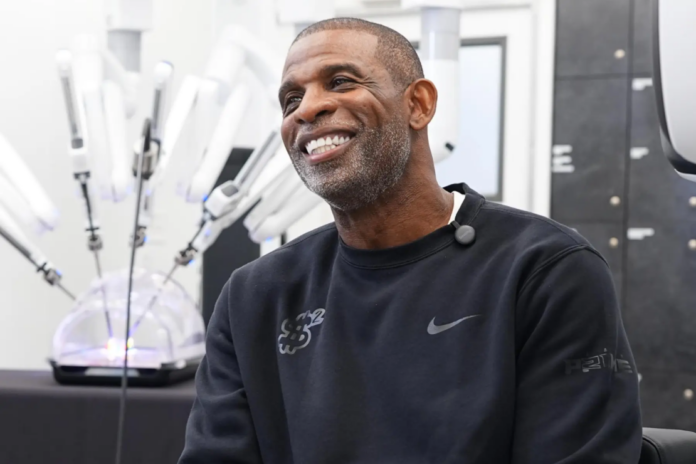 Colorado head football coach Deion Sanders talks about working the Da Vinci robotic surgical machine used to remove his cancerous bladder last year during a demonstration of the device Tuesday, June 23, 2026, in Boulder, Colo. (AP Photo/David Zalubowski)