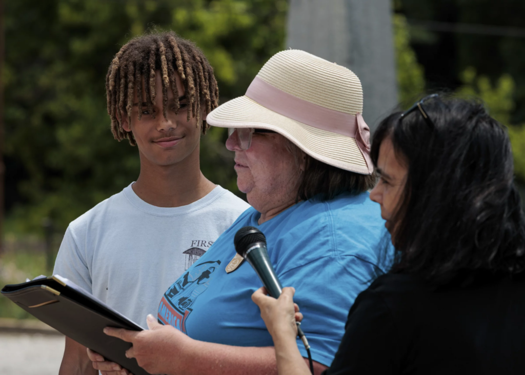 Elizabeth Kerwin speaks at the America 433+ teach-in at Harpers Ferry National Historical Park alongside her son, Daniel Nisbett, 13. KT Kanazawich for NPR