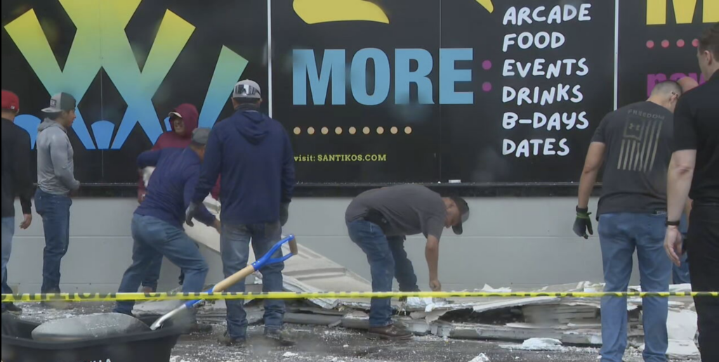 Workers clear debris outside the Santikos Palladium theater at The Rim after a tornado damaged the building Wednesday morning.