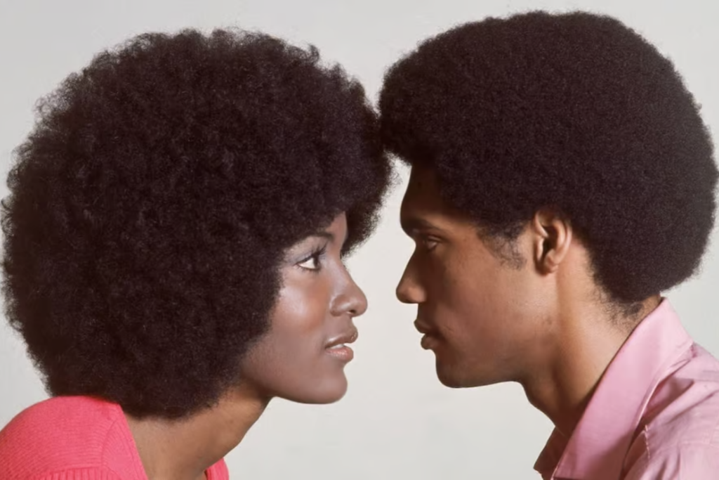 A young Afro-American couple with afro hairstyles stand face to face, circa 1970. George E. Johnson, who built a haircare empire with Afro Sheen and Ultra Sheen, died Monday at the age of 99. (Photo by Hulton Archive/Getty Images)