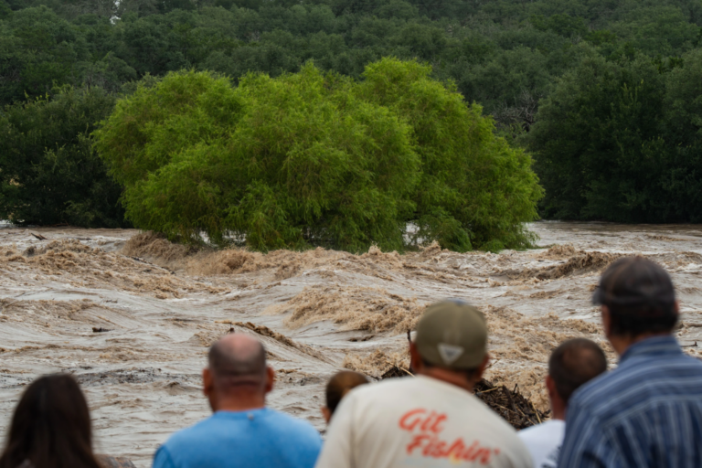People gather to watch as the Perdenales River floods Ranch Road 1623 in Stonewall, Texas, Thursday, July 16, 2026. (Mikala Compton/Austin American-Statesman via AP)