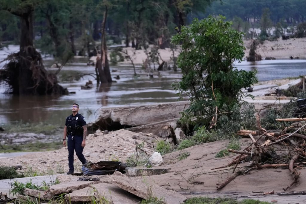 A police officer walks along the Guadalupe River after a series of storms on Friday, July 17, 2026, in Kerrville, Texas. (AP Photo/Gerald Herbert)