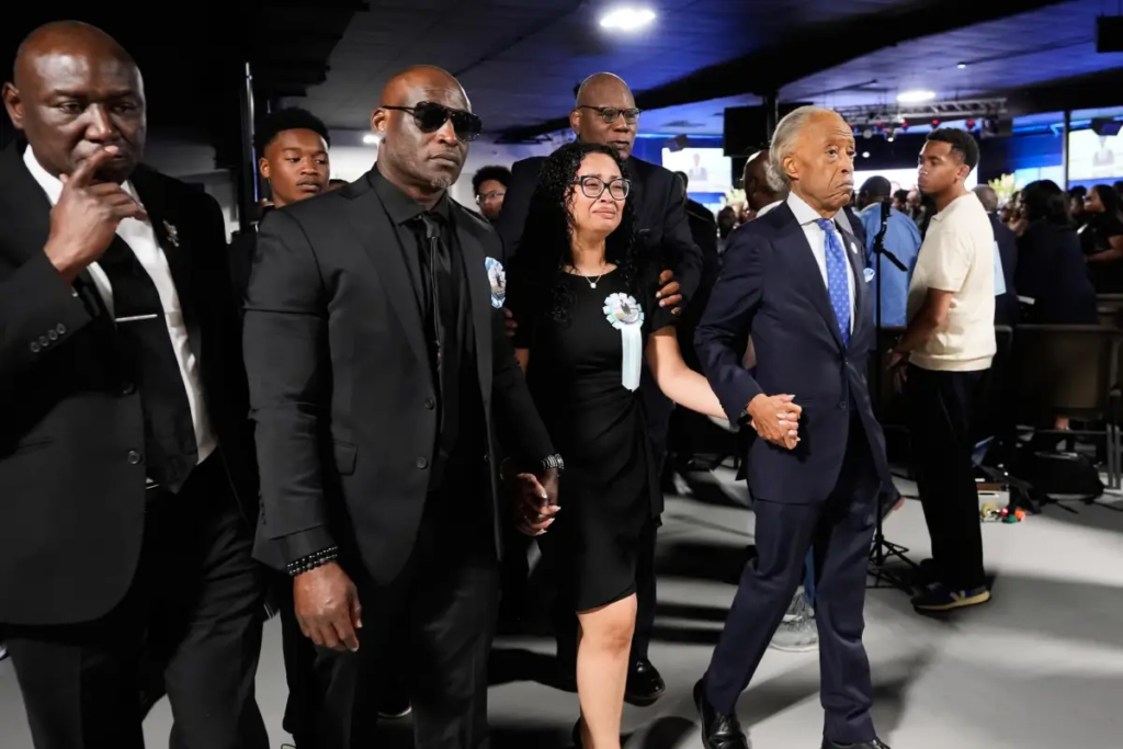 Christine Wonsley, center, walks with Rev. Al Sharpton, right, her husband Elmore, second from left, and attorney Ben Crump, left, during a memorial service for her son Nolan Xavier Wells, an 18-year-old found dead after taking a July 4 boat trip with friends on Monday, July 20, 2026, in Ocean Springs, Miss. AP Photo/Gerald Herbert