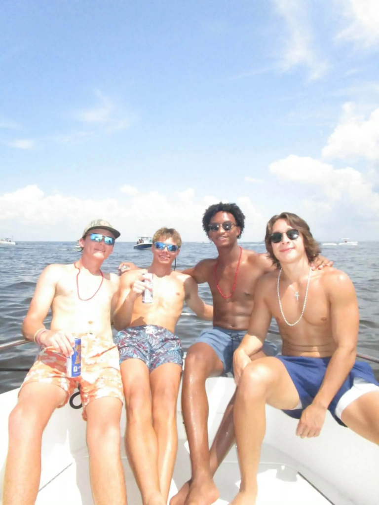 Nolan Wells, second from the right, and three friends sit shirtless on a boat. Facebook / Christine Wonsley