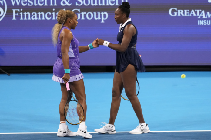 Serena Williams, left, first bumps Venus Williams, right, both of the United States, during a women's doubles match against Marta Kostyuk, of Ukraine, and Peyton Stearns, also of the United States, at the Cincinnati Open tennis tournament, Monday, Aug. 17, 2026, in Mason, Ohio. (AP Photo/Kareem Elgazzar)